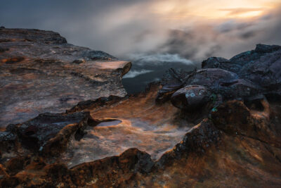 A beautiful sunset at lincoln's rock, blue mountains featuring rugged terrain and flowing low clouds.