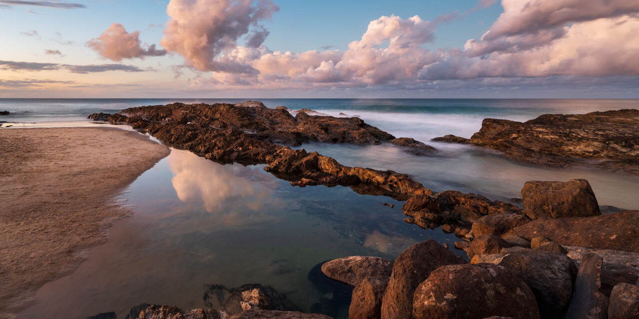 Gentle waves meet a blush-toned sky at Snapper Rocks, a tranquil moment in pink serenity.