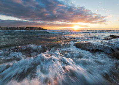 The sun's rays illuminate playful waves and foam at Bondi Beach, ideal for a lively ocean art print.