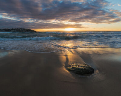 The first light of sunrise bathing Bondi Beach in a golden glow, perfect for an ocean artwork display.