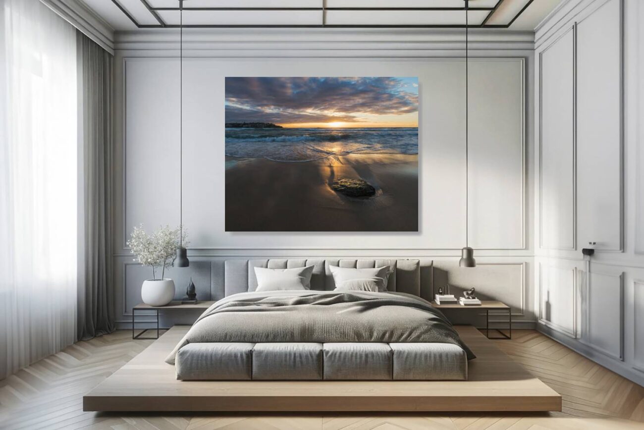 The bedroom features canvas art depicting the golden glow of sunrise at Bondi Beach, offering a peaceful and luminous seascape. This artwork fosters a calming environment, ideal for relaxation and inspiration, reflecting the serene start of a new day.