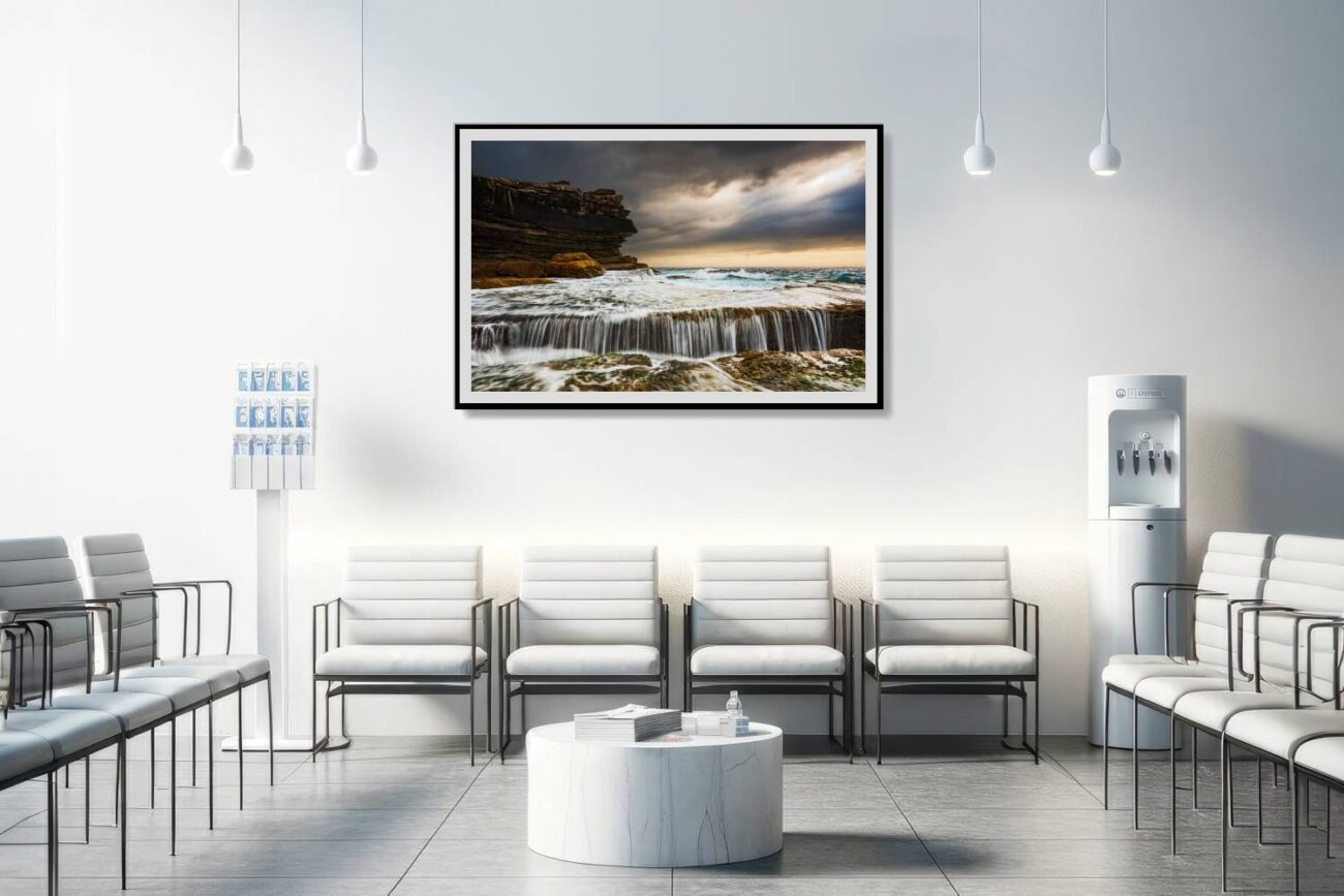 The medical office is adorned with a framed piece depicting the stormy sunrise at Clovelly Beach, showing the water's forceful journey over rocks. This powerful and elegant artwork contributes to an atmosphere of dynamism and natural beauty, offering a captivating visual experience for patients and staff.