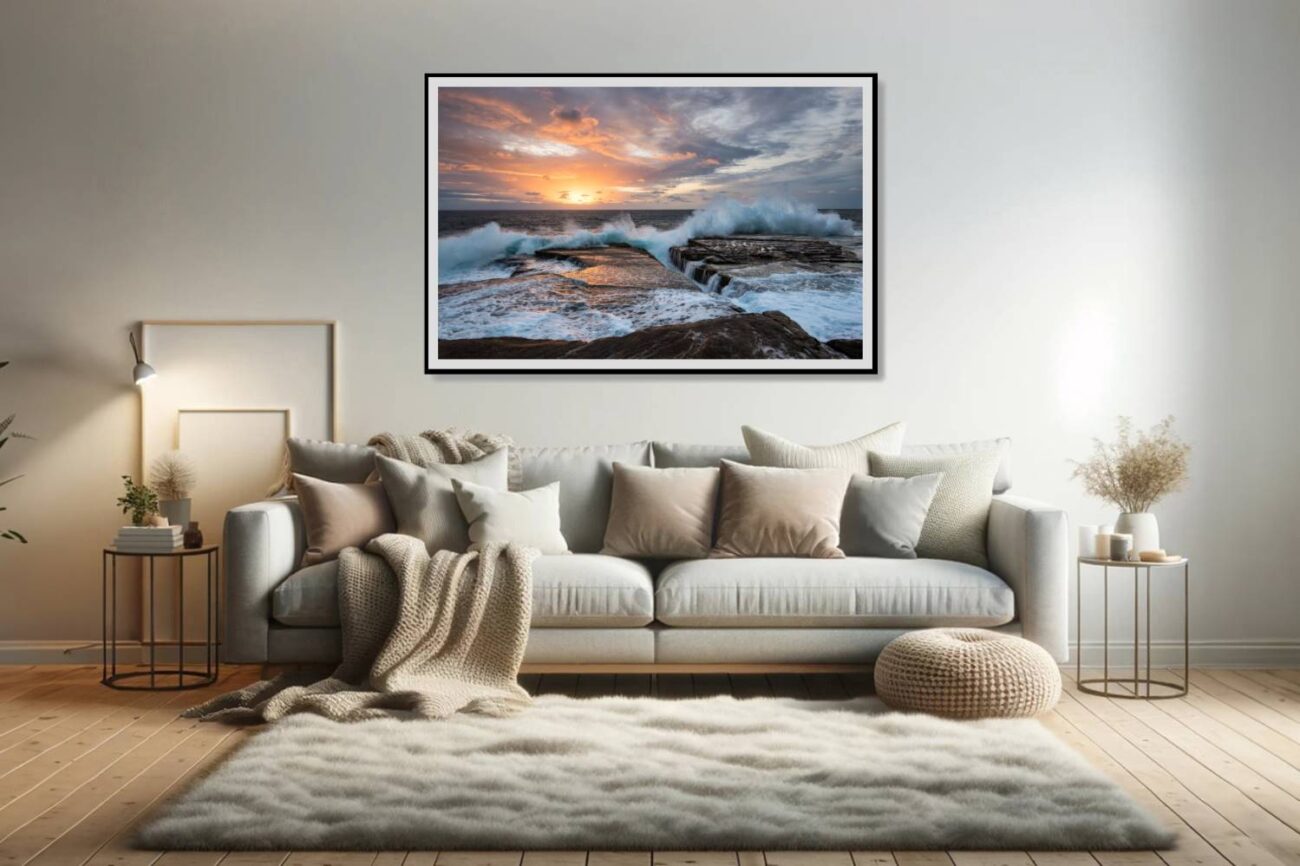 In the living room, a framed art piece displays the intense waves at Clovelly Beach at sunrise, under a warm, glowing sky, titled "Dawn Chorus." This artwork adds a vibrant and energetic atmosphere to the space, capturing the essence of a new day's beginning with nature's powerful display.