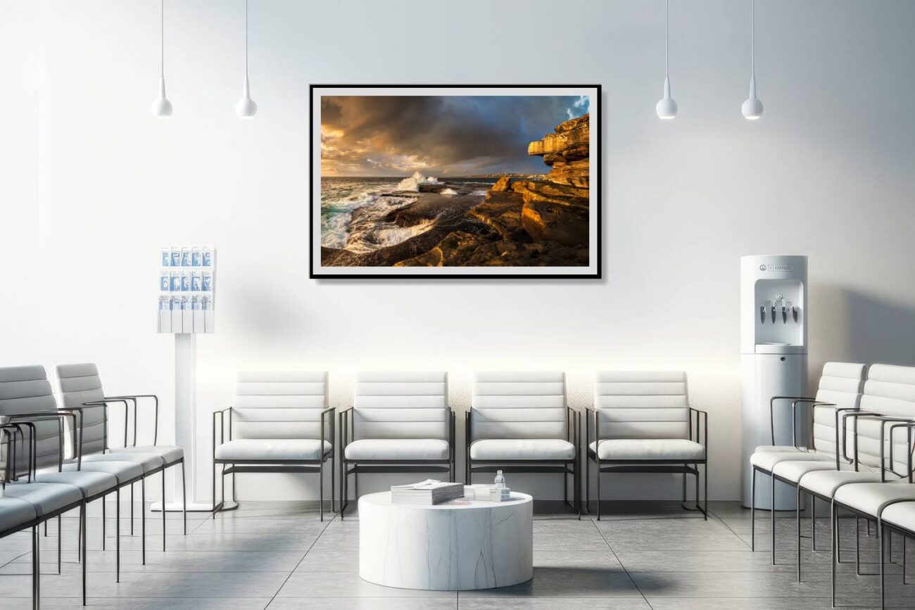 In the medical office, a framed piece captures the vibrant sunrise at Clovelly Beach, emphasizing the dynamic interaction of light, rocks, and waves.