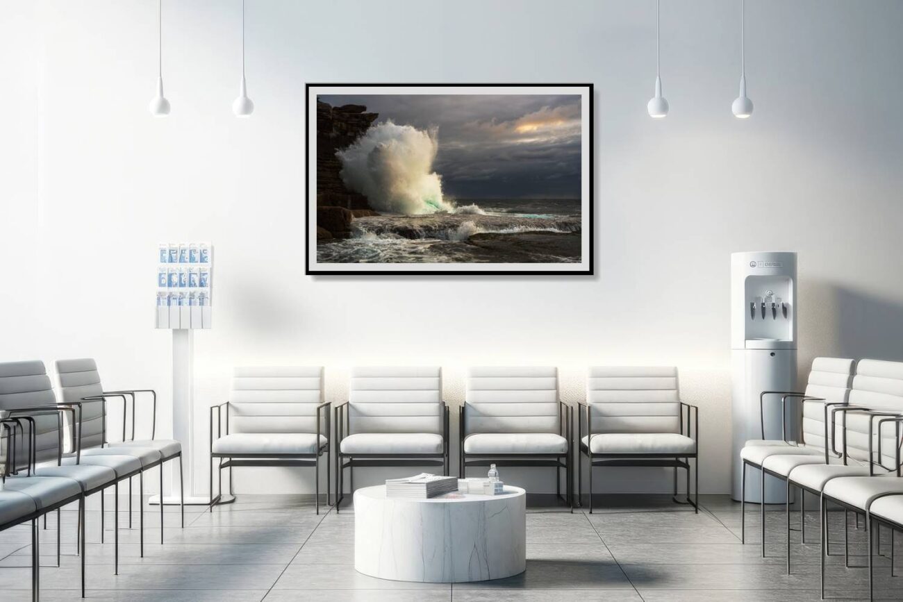 The medical office is adorned with a framed art piece showing a massive wave crashing against the cliffs at Clovelly Beach during sunrise, under a backdrop of storm clouds. This captivating scene provides a sense of dynamism and the sublime beauty of nature, enhancing the environment for patients and staff.