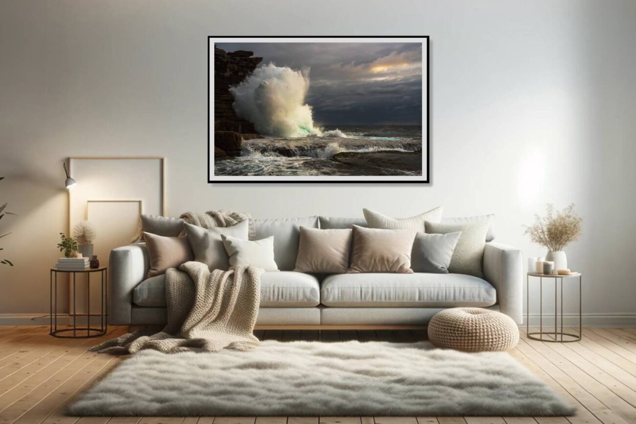 The living room features a framed art piece capturing a massive wave crashing against the cliffs at Clovelly Beach during sunrise, set against dark storm clouds. This dramatic and powerful scene adds an element of nature's intensity and beauty to the room, creating a focal point that invites viewers to contemplate the force of the ocean.