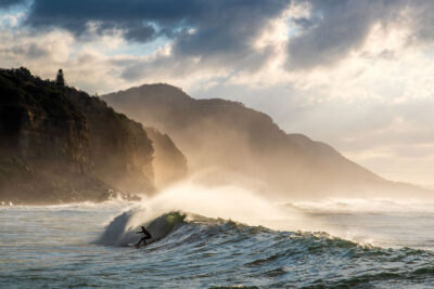 A surfer rides a wave at Coalcliff Beach, immortalized in a moment of oceanic zen artwork.