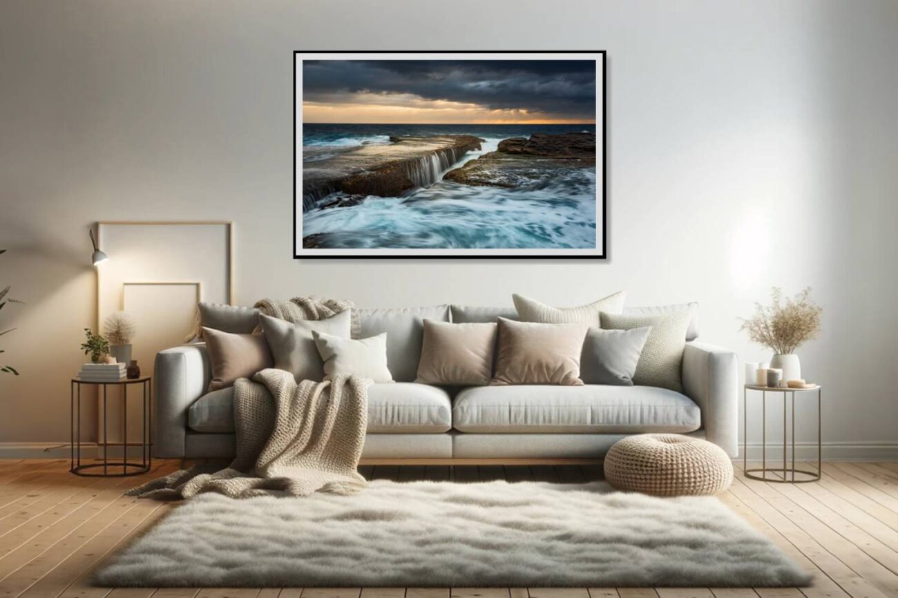 In the living room, a framed art piece captures the dynamic scene of sunrise at Clovelly Beach, where waves crash like waterfalls, creating a powerful yet elegant visual suited for storm artwork. This piece adds a dramatic and invigorating element to the space, inviting viewers to feel the energy and majesty of the ocean.