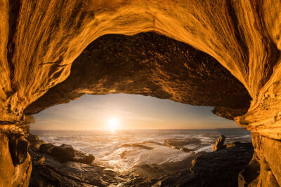Sea cave at Clovelly Beach overlooking the sunrise. The cave entrance and the sun resemble the eye. Orange wall art.