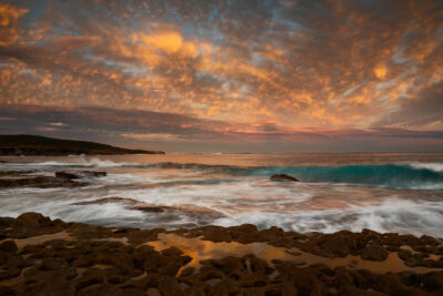 Sunset illuminates the clouds and turquoise waters of Voodoo Point with fiery hues.