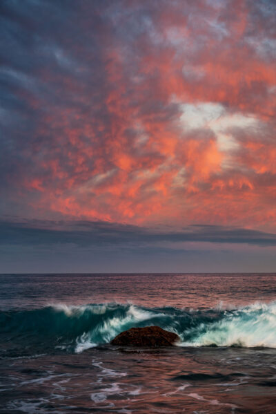 Crimson and magenta hues dominate the sunset sky above the passionate waves at Voodoo Point.