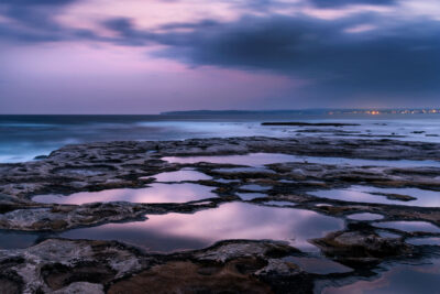 Indigo and violet hues of twilight reflecting on serene tide pools at Potter Point.