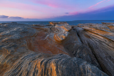 Dawn at Potter Point, with a rugged terrain glowing like Mars under a purple sky.