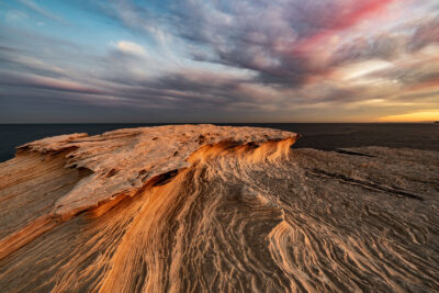 Golden sunlight highlighting the textured layers of a 'Petrified Wave' sandstone formation.