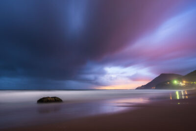 Serene Stanwell Beach at twilight with a vibrant purple sky reflecting in the water, ideal for ocean art.