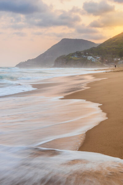 Golden sunrise light bathing Stanwell Beach with gentle waves, perfect for ocean artwork.