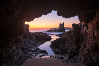 Sunrise Amphitheatre – A serene sunrise view through a coastal cave at Kiama, with warm hues reflecting on calm waters.