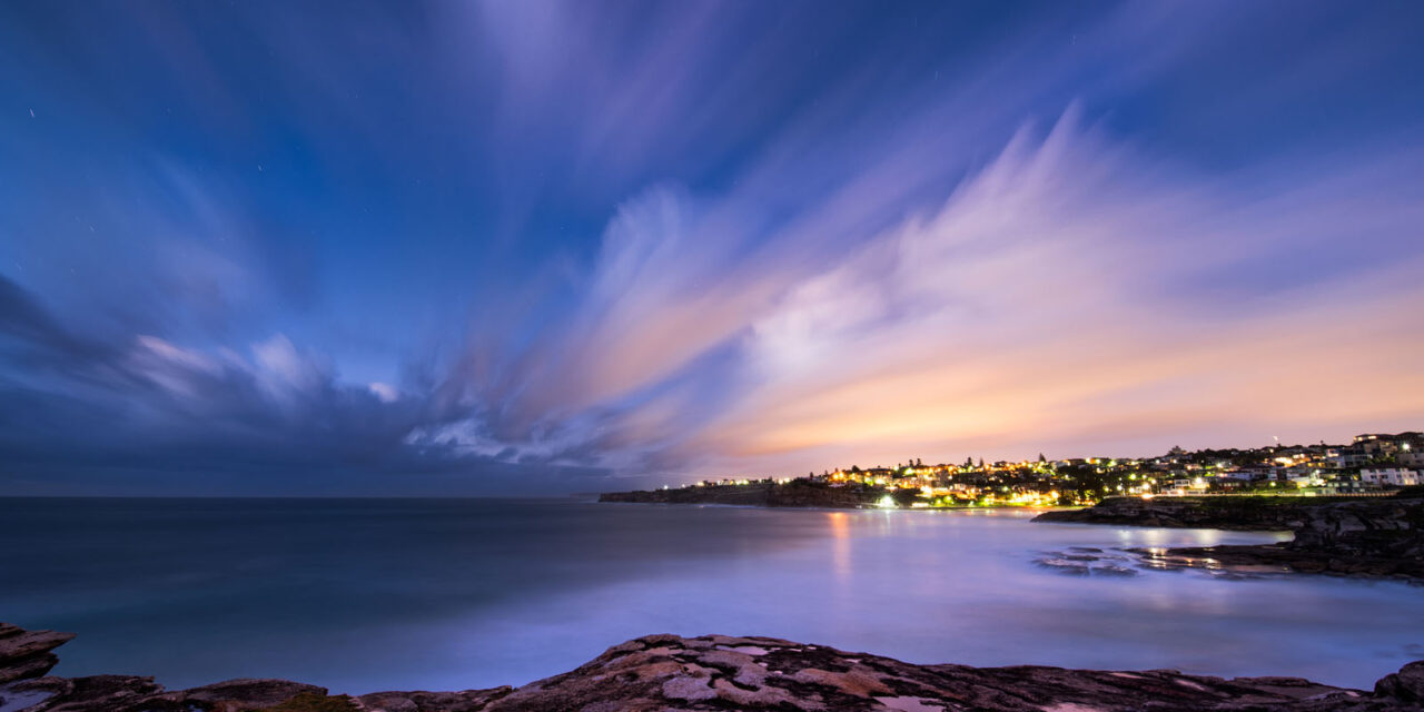 The serene twilight sky in hues of violet and blue over the calm coastal waters of Sydney.