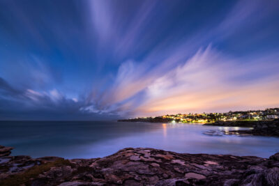 The serene twilight sky in hues of violet and blue over the calm coastal waters of Sydney.