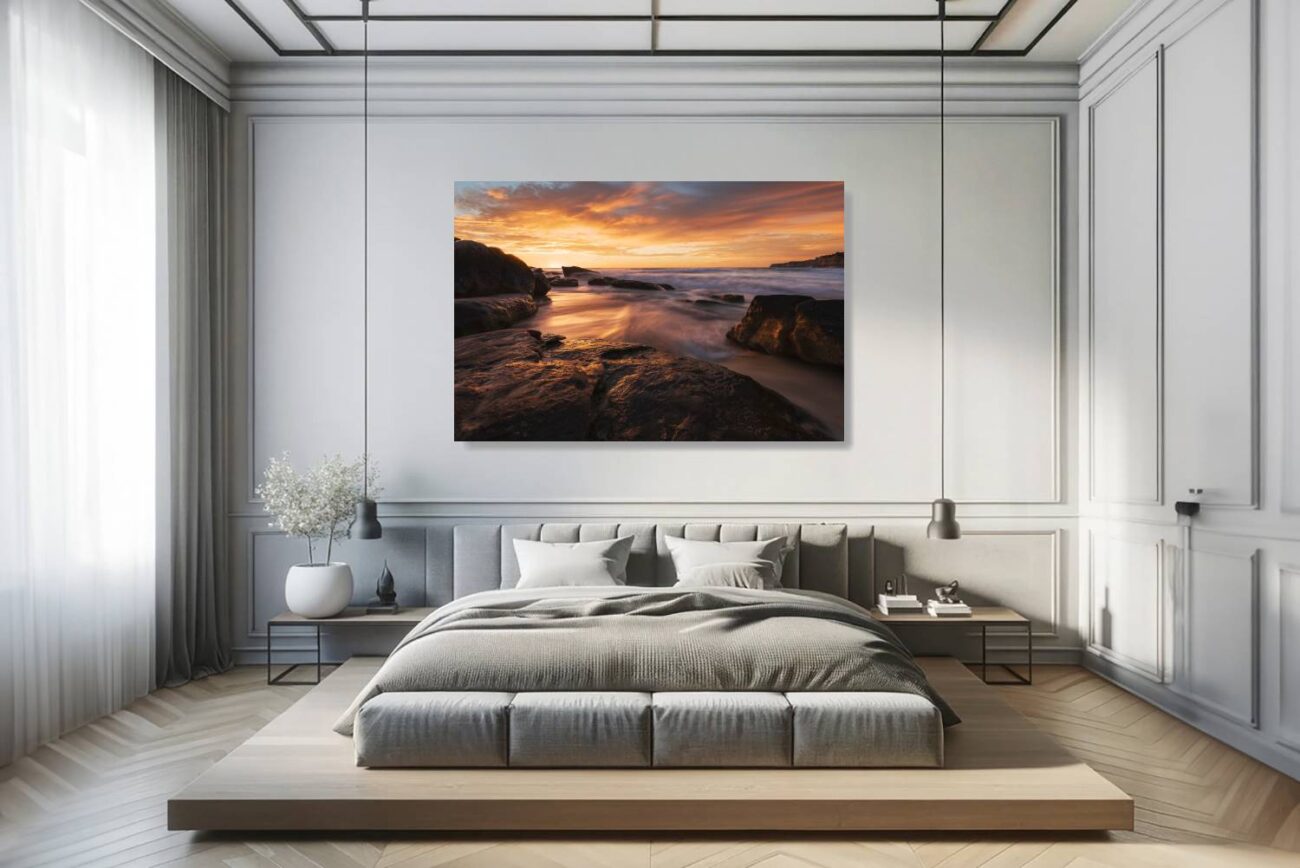 The bedroom's canvas art presents "Fiery Shores," depicting the sunset's glow on Tamarama Beach's waves and rocks. This artwork adds a tranquil yet energizing element to the room, ideal for inspiring relaxation and reflection in a vibrant natural setting.