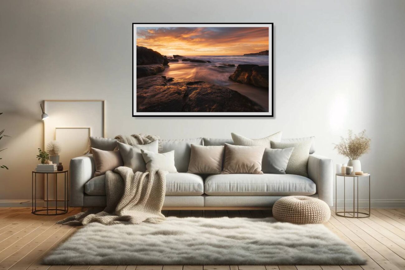 In the living room, a framed ocean artwork titled "Fiery Shores" captures the sunset at Tamarama Beach, where the light illuminates the waves and rocks. This piece brings warmth and dynamic beauty to the space, showcasing the vibrant interplay of light and nature.