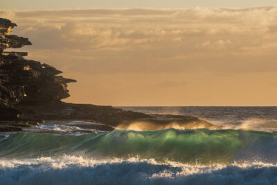 Rocky cliff silhouettes against the sunrise at Tamarama Beach, highlighting the sculptural beauty of nature in wave art.