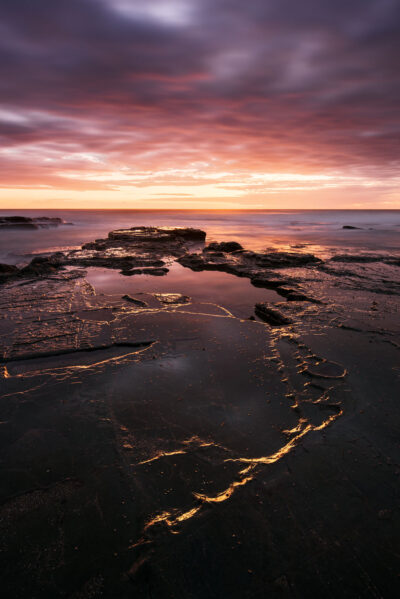 Golden light tracing patterns in the rocks at Bulgo Beach during sunrise. Amber wall art.