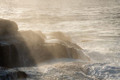 A sunrise at Mahon Pool illuminates the ocean spray, creating a sparkling 'Diamond Spray' against the morning sky.