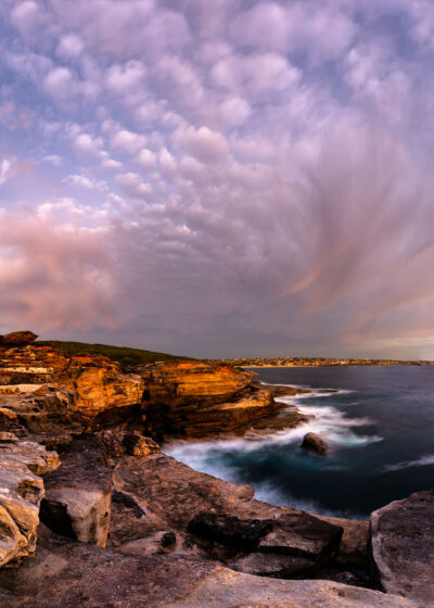 Pink cloud formations at sunset creating a harmonious display above Malabar's rocky coast in pink wall art.