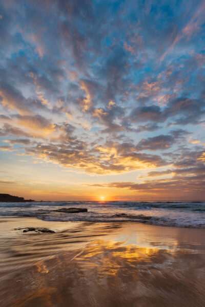 The sun rises at Maroubra Beach, casting a colorful glow over clouds and wet sand in this peaceful ocean sunrise artwork.
