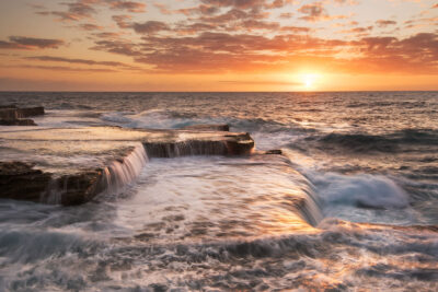 Dynamic sunrise over Maroubra ocean pool with golden light reflecting on turbulent water, ideal for vibrant coastal wall art.
