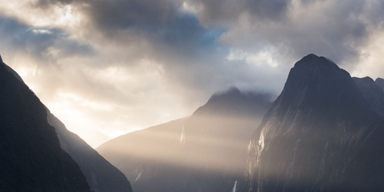 Sunlight illuminates the peaks and casts gentle shadows over Milford Sound.